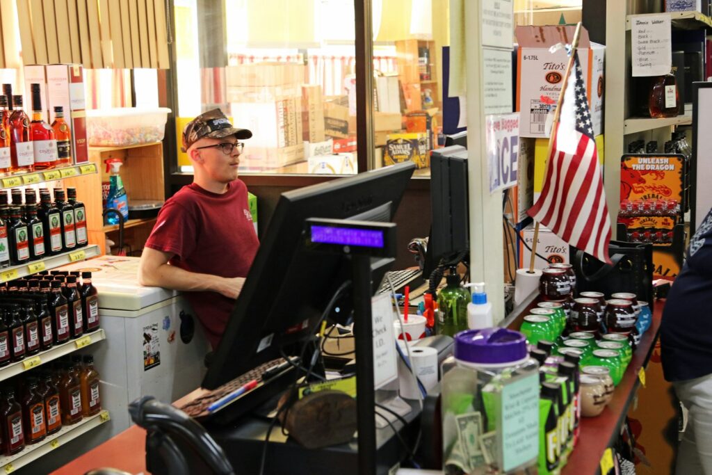 Young man working at a store checkout counter, representing trade counter roles in retail and merchant sectors