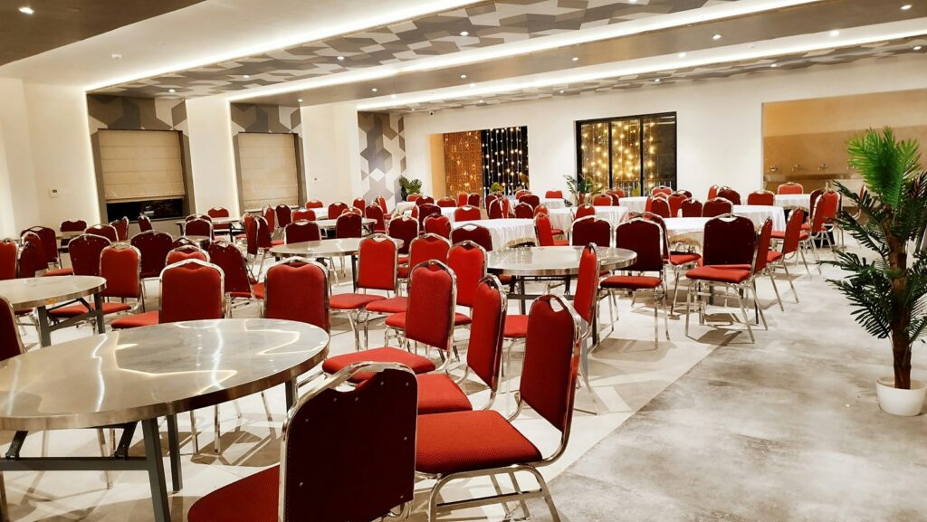 Empty banquet hall with red chairs and round tables, ready to be checked before contract signing