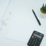 Black calculator beside a pen on blank white paper, suggesting capital calculations for a regulated firm