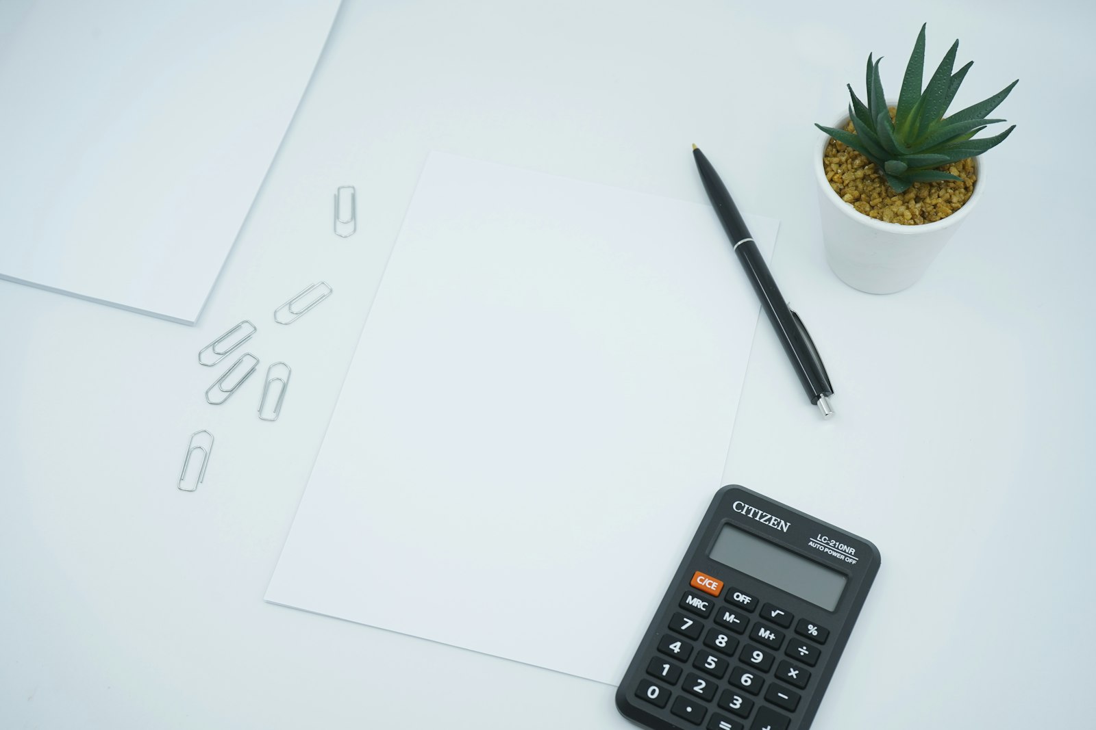 Black calculator beside a pen on blank white paper, suggesting capital calculations for a regulated firm