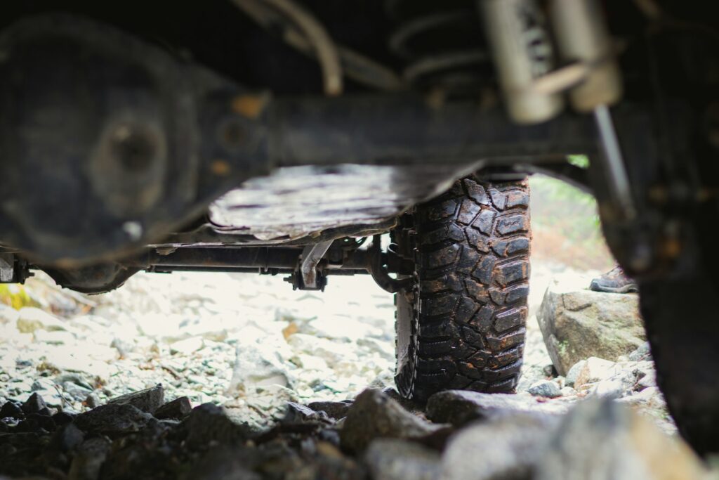 View from underneath a 4x4 showing wet, knobbly tyres resting on rocks